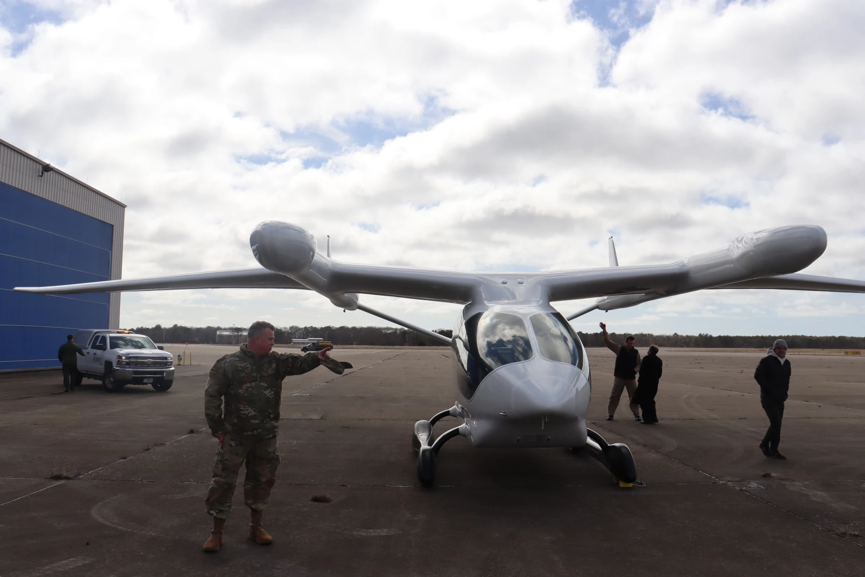 Joint Base Cape Cod Executive Director and Retired Brigadier General Christopher Faux stands in front of the fully-electric aircraft Alia after a demonstration at the 102nd Intelligence Wing.